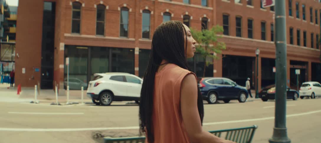 Woman pulls her luggage as she walks on a downtown sidewalk