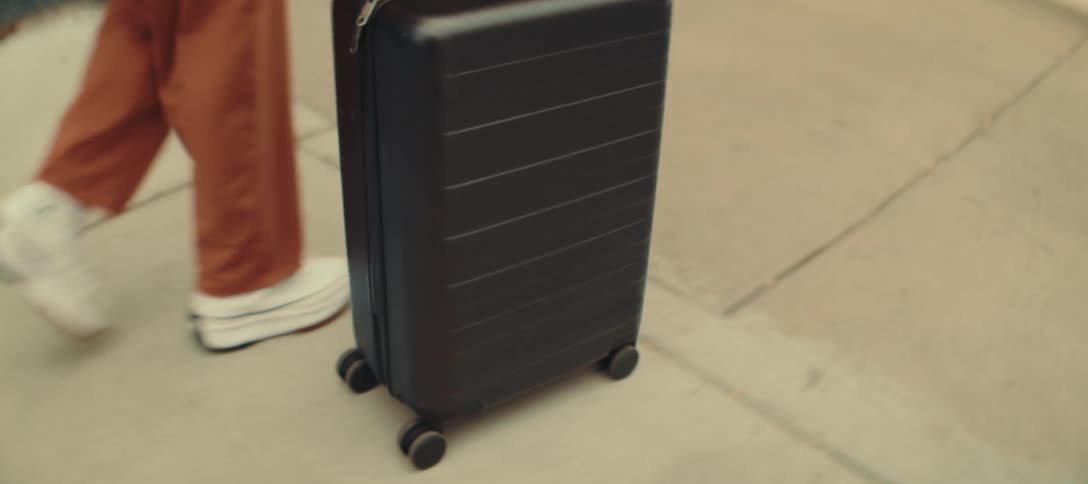Woman pulls her luggage as she walks by buildings on a downtown sidewalk