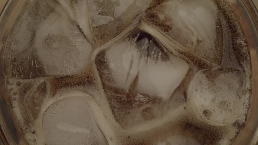 Ice cubes float in a fizzy drink seen from above