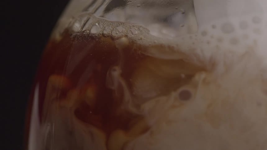 A white liquid is poured into a bottle with a brown foamy liquid mixing the two liquids