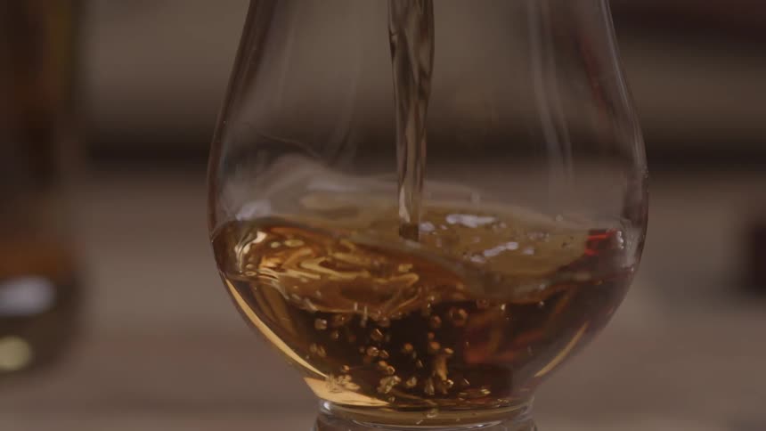 Wine is poured into a glass as a person picks it up from the table