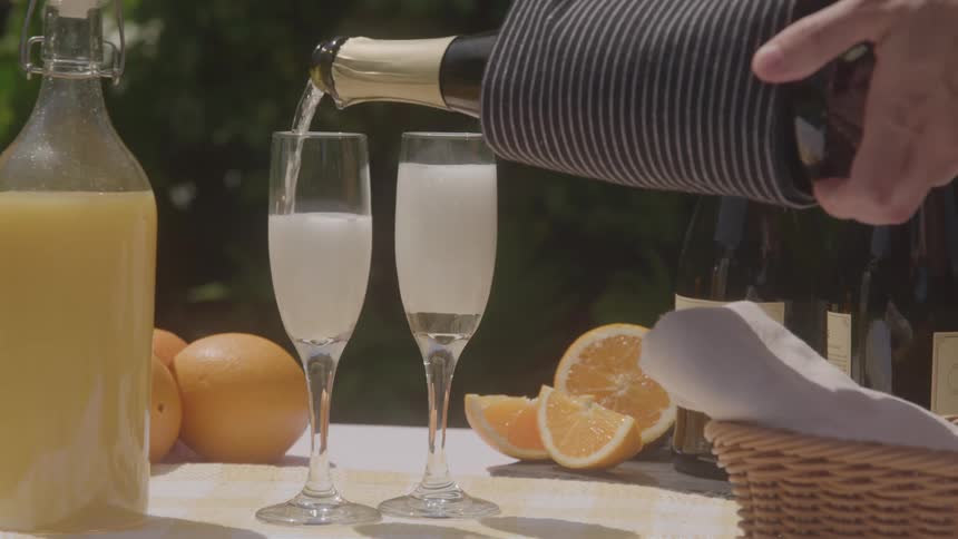 Hands pouring champagne into empty glasses on a table