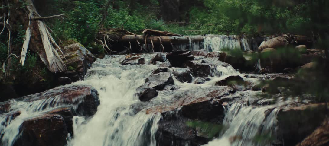 A river is flowing downhill over rocks as a waterfall