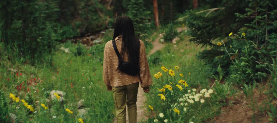 Woman walking alone on a forest trail surrounded by greenery