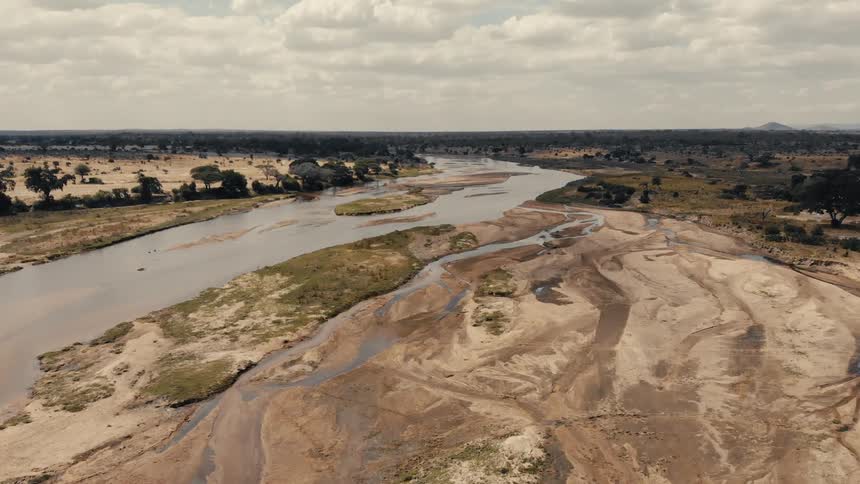 Wide river with sandy banks and dry patches amid savanna vegetation