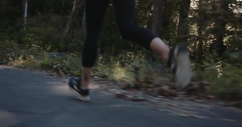Woman running on a road through the woods