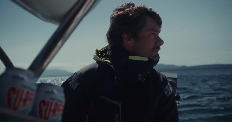 Man in warm clothing looks at the horizon while sailing on a boat