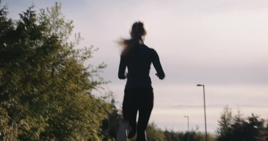An athletic woman runs along a pathway during the daytime