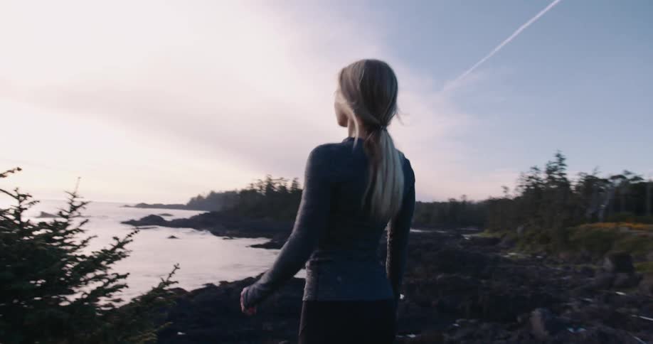 Woman runs outdoors near the coast during sunset