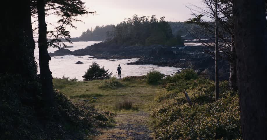 Person runs along a trail toward the rocky coastline with the sea in the background