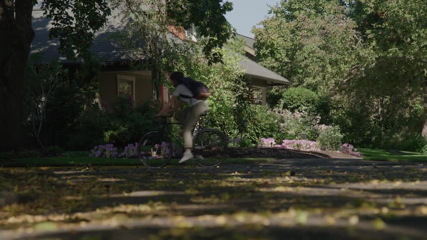 A woman rides her bike past the home