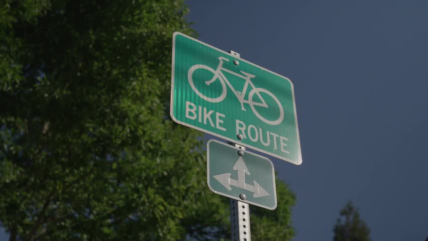 A bike route sign is under the clear sky