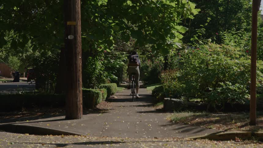 A man rides his bicycle on the sidewalk