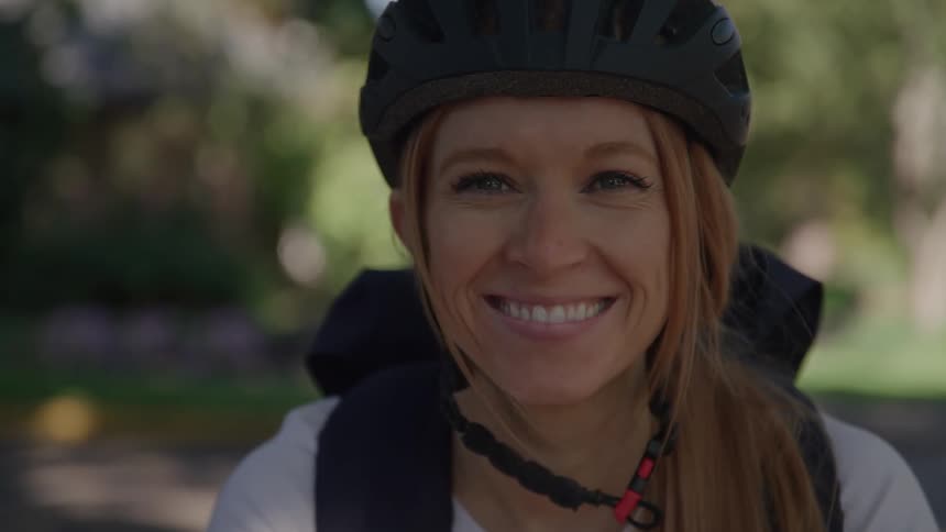 Smiling cyclist wearing a helmet and backpack outdoors