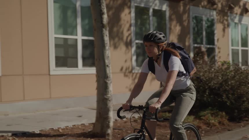 The woman rides her bike past the building