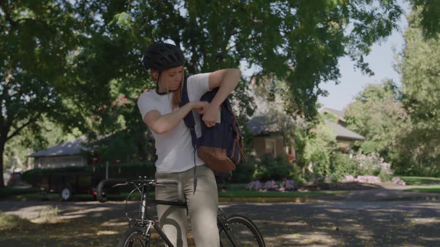 The girl puts her things away and rides her bike