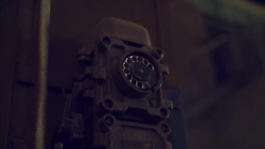 The rotary dial of an old fashioned dark rusted industrial telephone