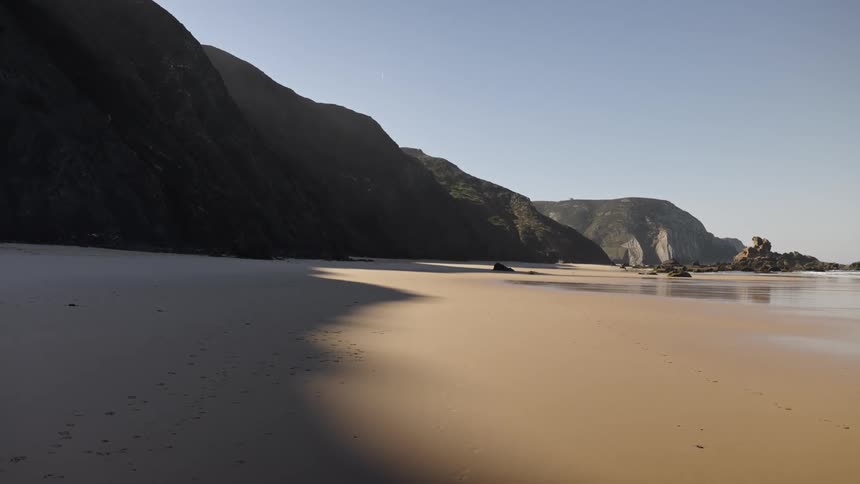 Deserted beach with mountain shadows cast on the sand