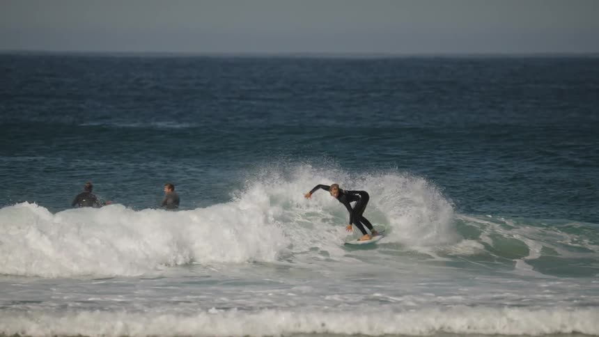 Surfer rides crashing waves in ocean under clear sky