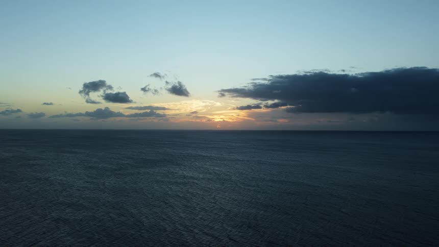 Ocean horizon at dusk with dark clouds contrasting against the soft sunlight