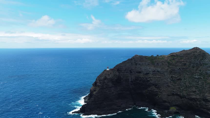 Aerial view of coastal cliff with lighthouse by ocean