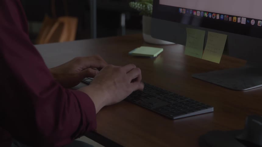 A person types on a keyboard at an office desk