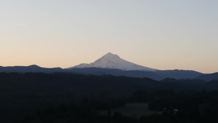 Snow covered mountain peak silhouetted against dusky sky