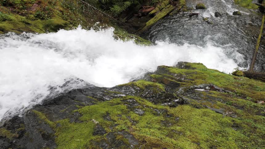 Stream of water flowing over mosscovered rocks