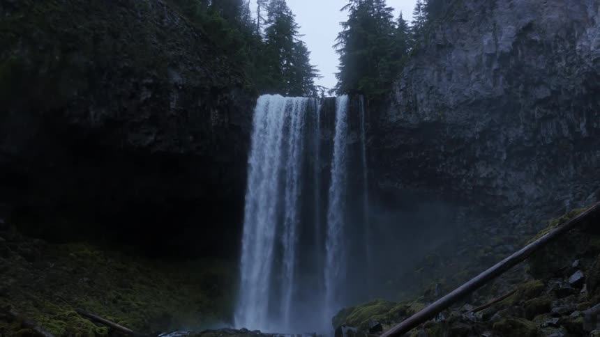 Waterfall flows over a cliff splashing into the river below