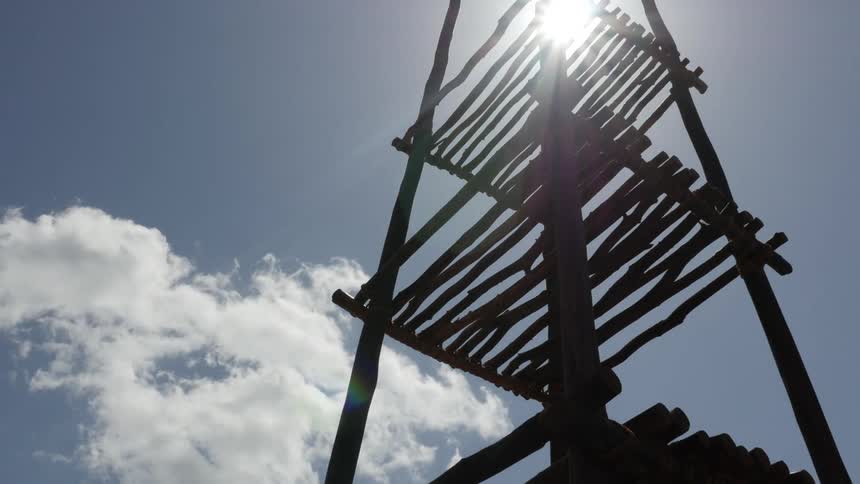 A wooden structure silhouetted against a bright sunlit sky