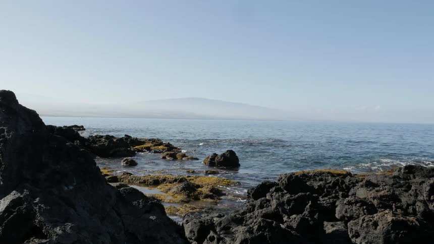 Waves roll into shore and splash against rocks along the coast