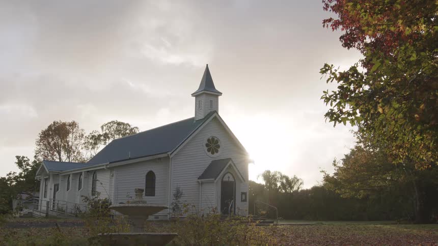 White wooden church lit by the sunset glow