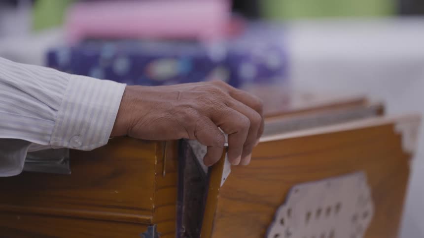 A person opens and closes the bellows of a wooden harmonium by hand