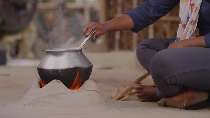 Indian woman cooking on clay stove using traditional method