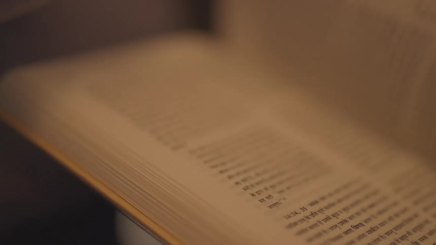 Hand flipping through a book with text in indian script