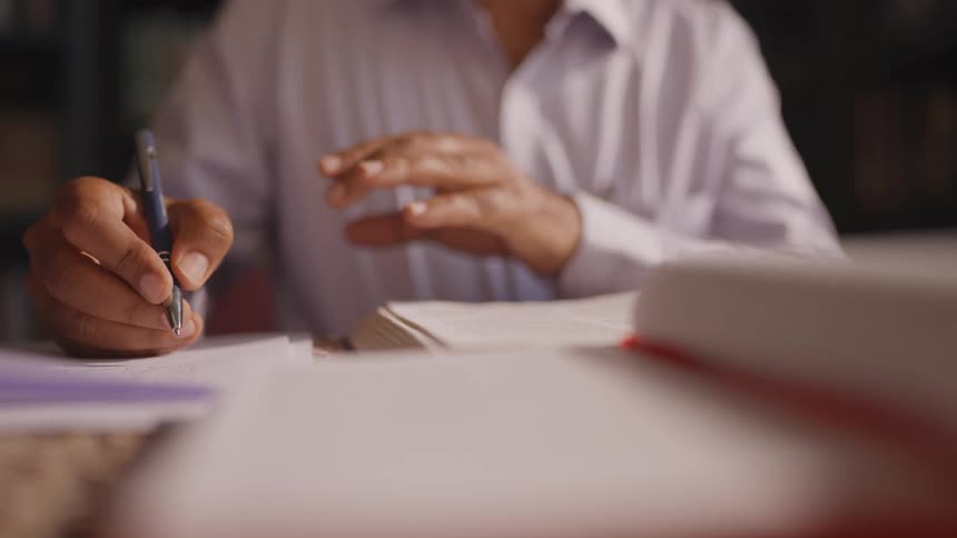 Based on the images from the video a closeup shot of a persons hands shows them signing papers the person is wearing a lightcolored collared shirt and uses a blue pen to write on a white sheet of paper on a clipboard