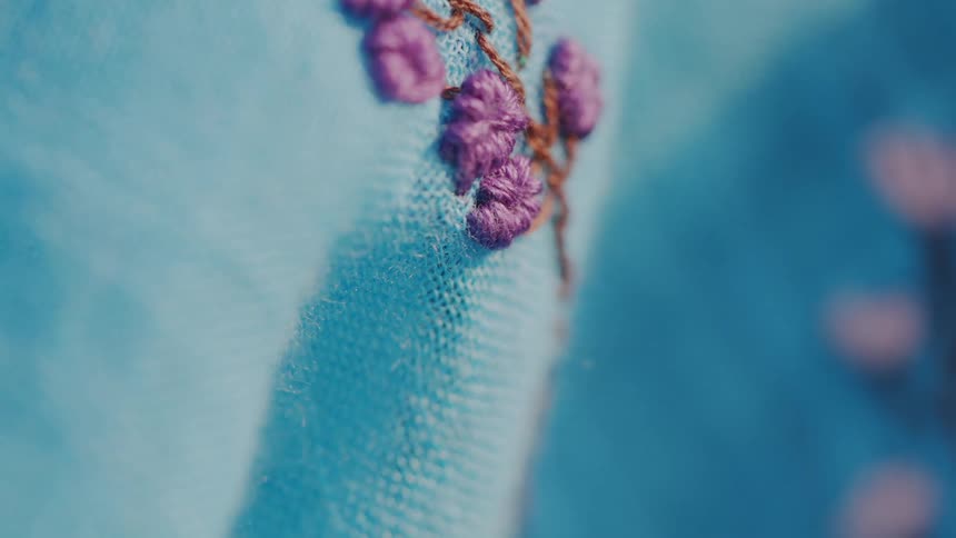 Purple flower embroidery on blue fabric