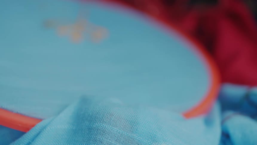 Based on the images from the video a closeup shot shows a light blue sheer fabric with small pink and purple embroidered flowers the fabric has a slightly wrinkled texture and is draped in soft folds
