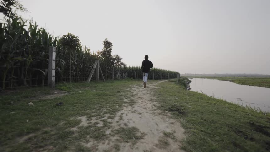 A person runs by the large field of crops