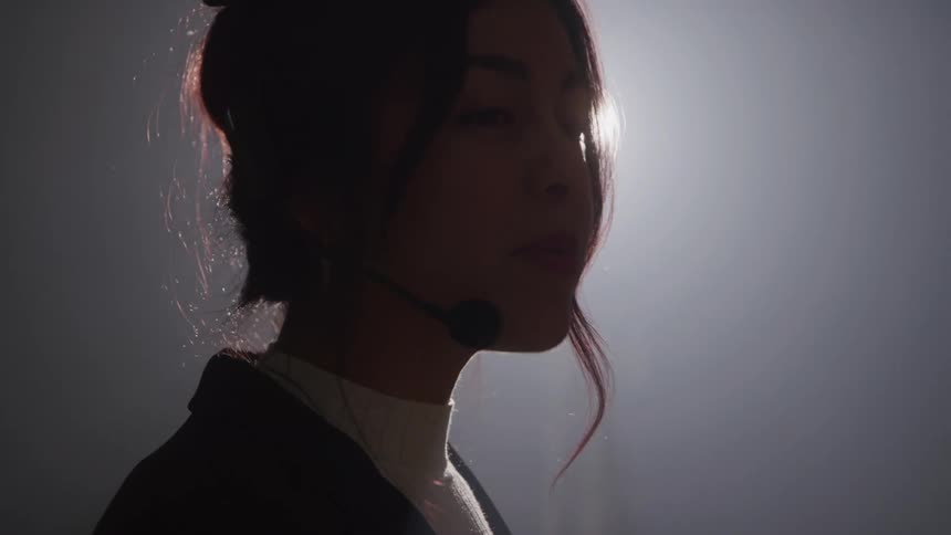 Woman wearing a headset microphone while speaking in a backlit setting
