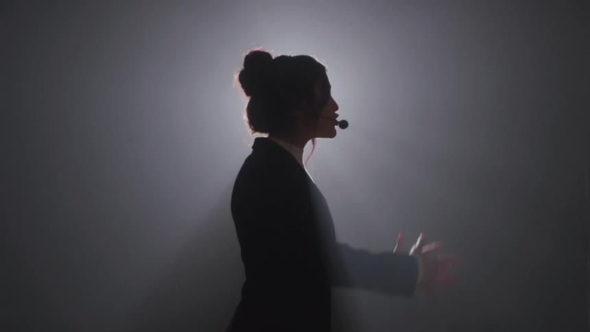 The woman is giving a speech on the foggy stage
