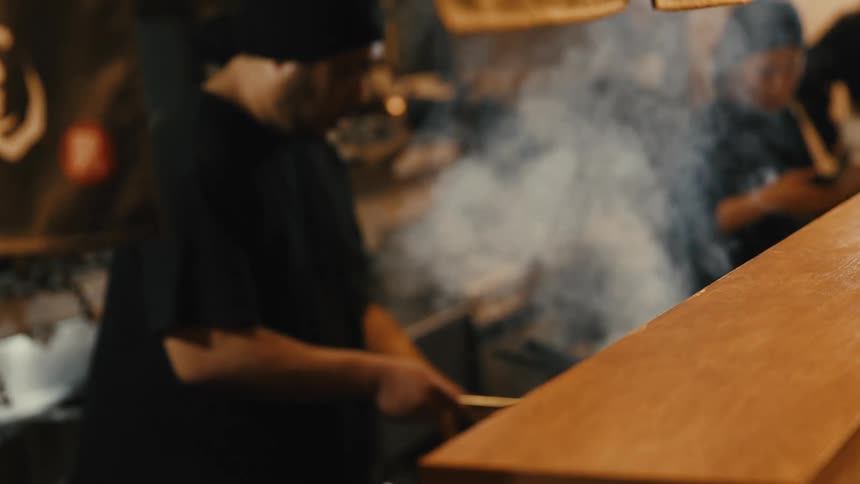 Chefs cooking in a smoky restaurant kitchen