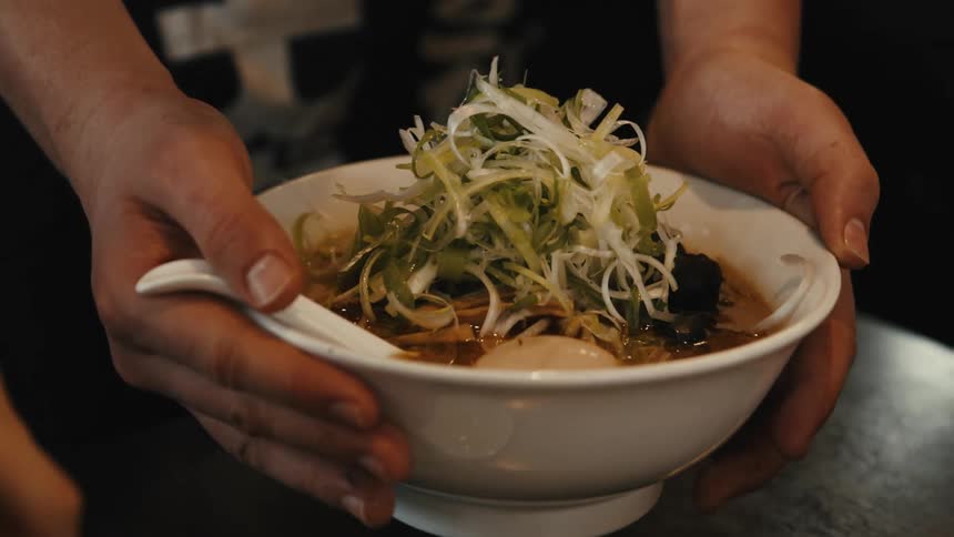 A woman serving vegetable soup on a dining table