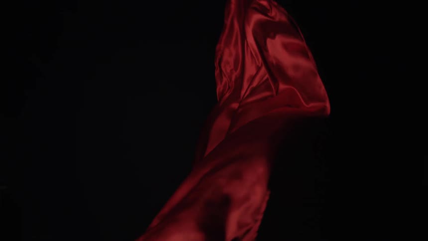 Red fabric flowing in waves against a dark background
