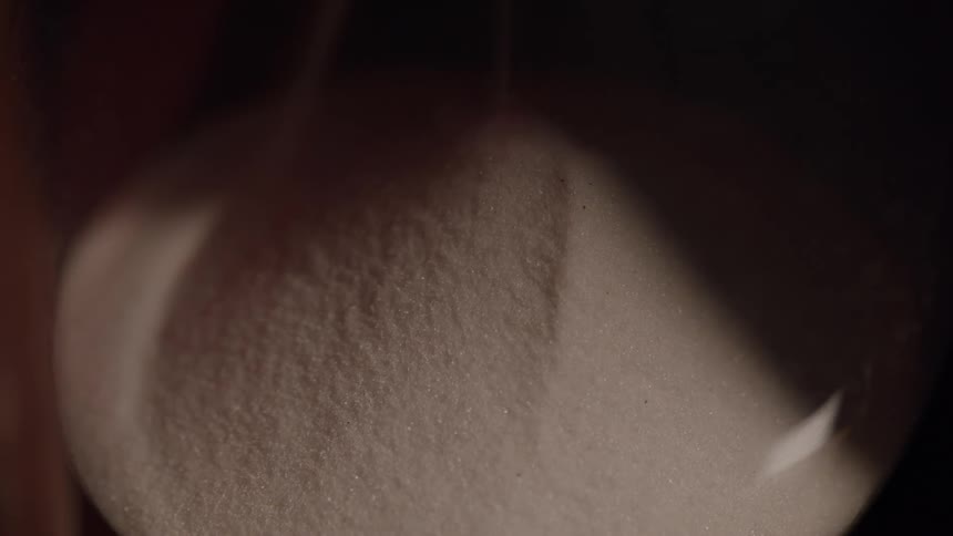 A lose up of a small mound of sand or sugar in shadows