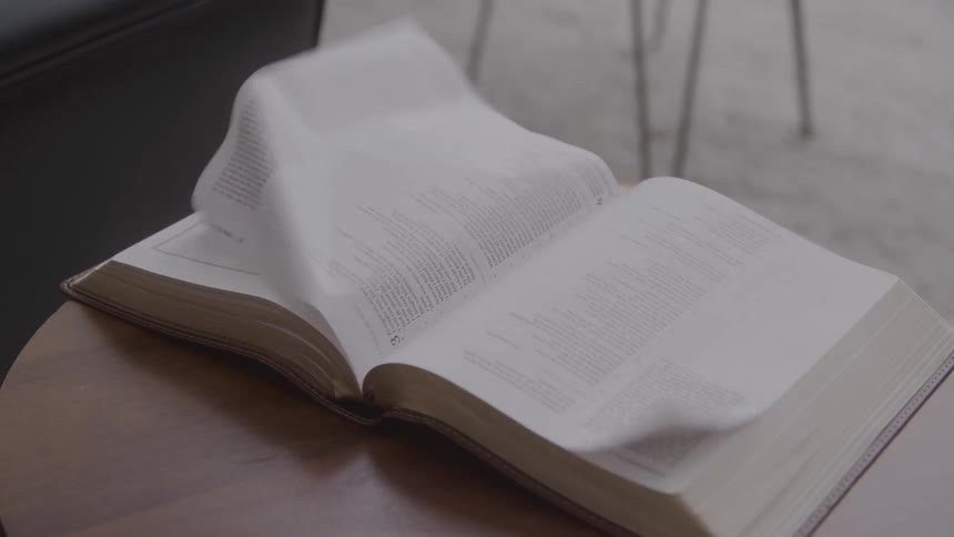 Pages of an open book left on a table outdoors blowing from the wind