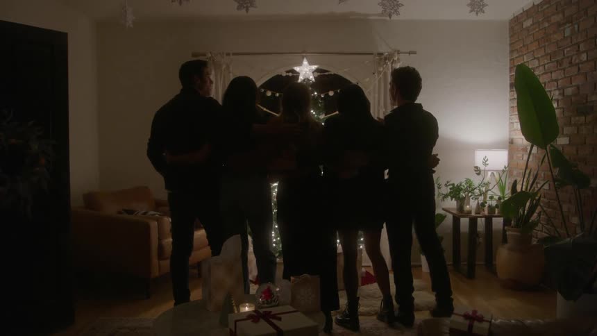 A group of friends celebrating the holidays together standing in a circle and admiring a large decorative star