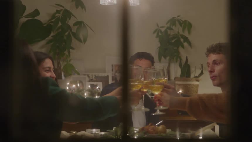 Based on the video a man and a woman are seen sitting at a dining table the table is set with food and drinks and the scene is lit with warm ambient lighting suggesting a dinner setting