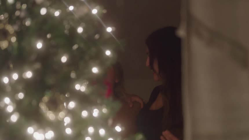 Two people smiling near a lit christmas tree