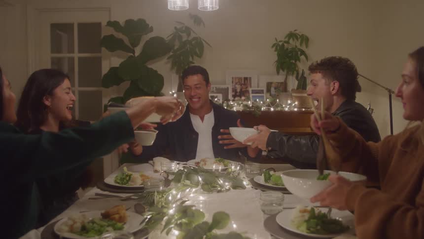 Group of friends shares a lively meal around a table decorated with lights